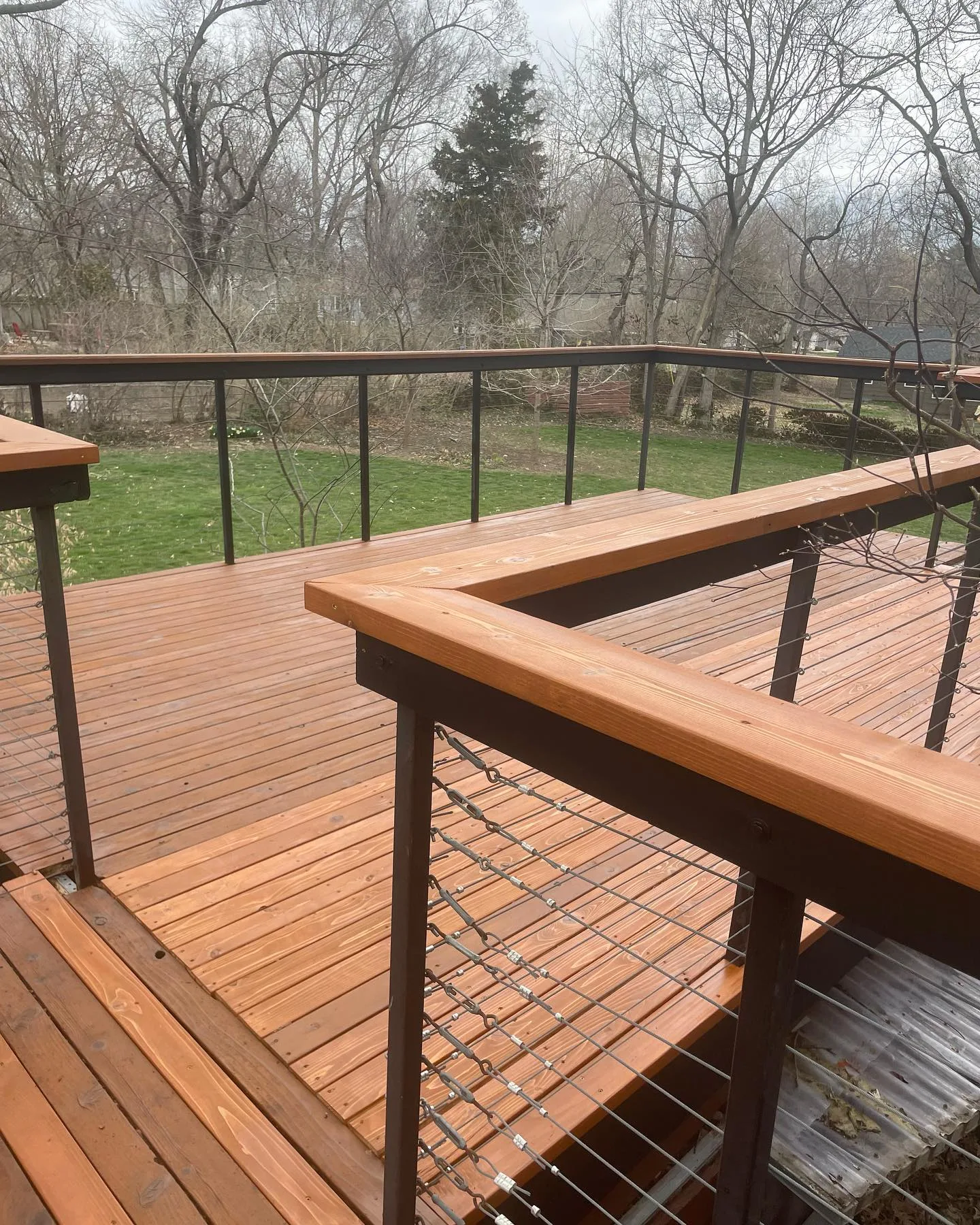 L-shaped cedar deck with cable railing freshly stained in Blue Springs, MO — overcast spring day