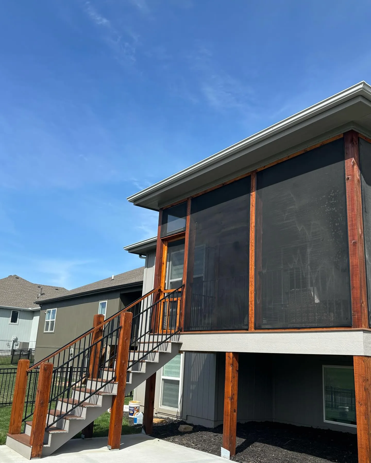 New screened porch with freshly stained cedar posts and framing in Smithville, MO — blue sky, new construction