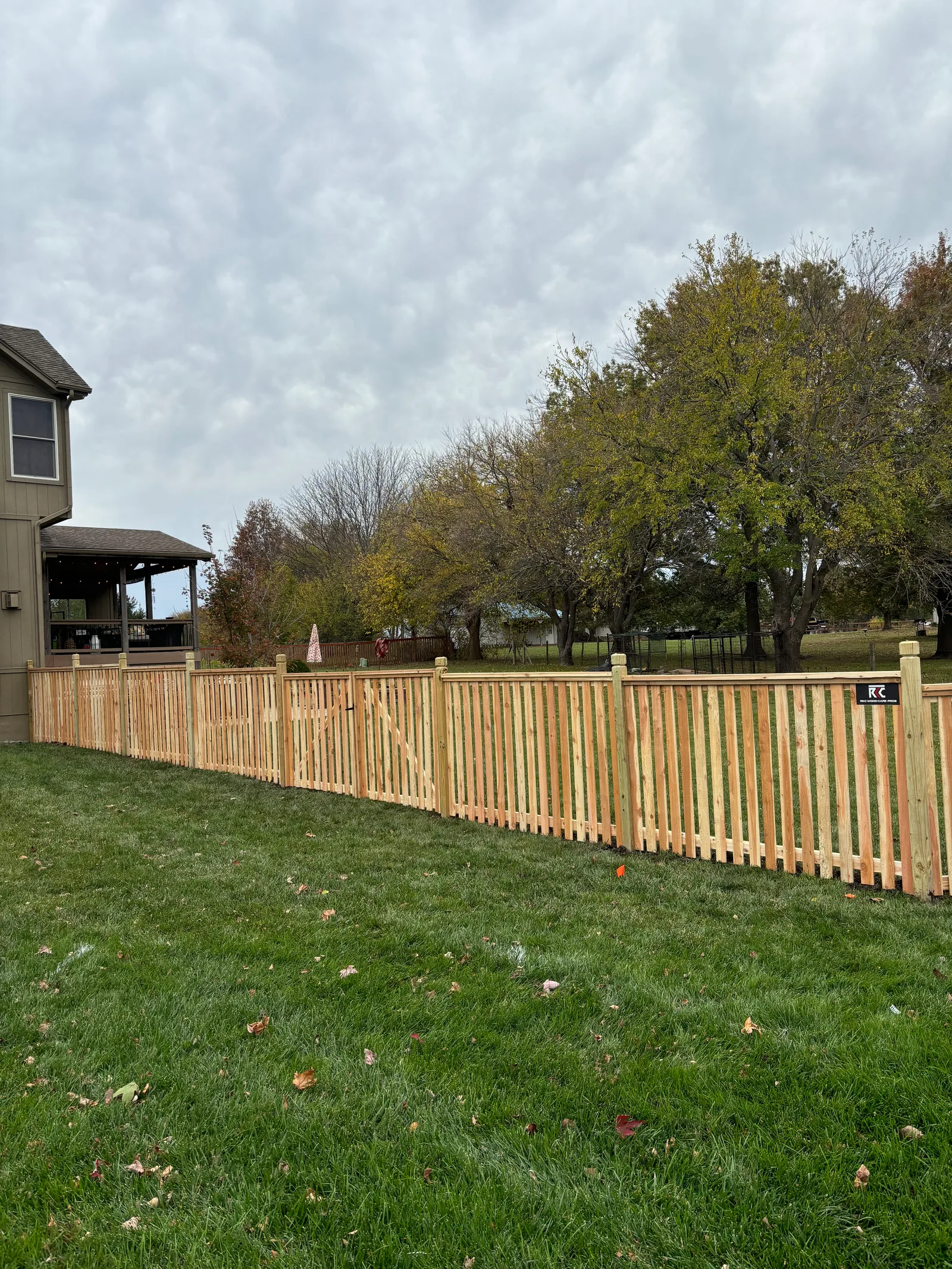 New cedar privacy fence in Gardner, KS on a cloudy November day — fresh boards, horizontal slat detail